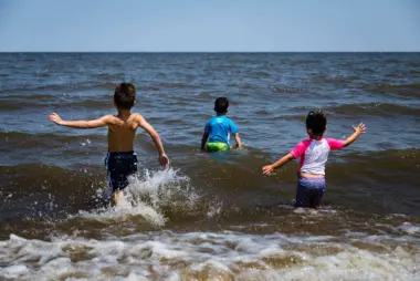 Three children play in the water at Fort Smallwood Park, located where the Patapsco River meets the Chesapeake Bay.